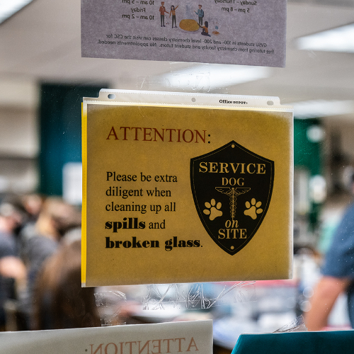 sign on the door warns of a service dog and to clean up broken glass