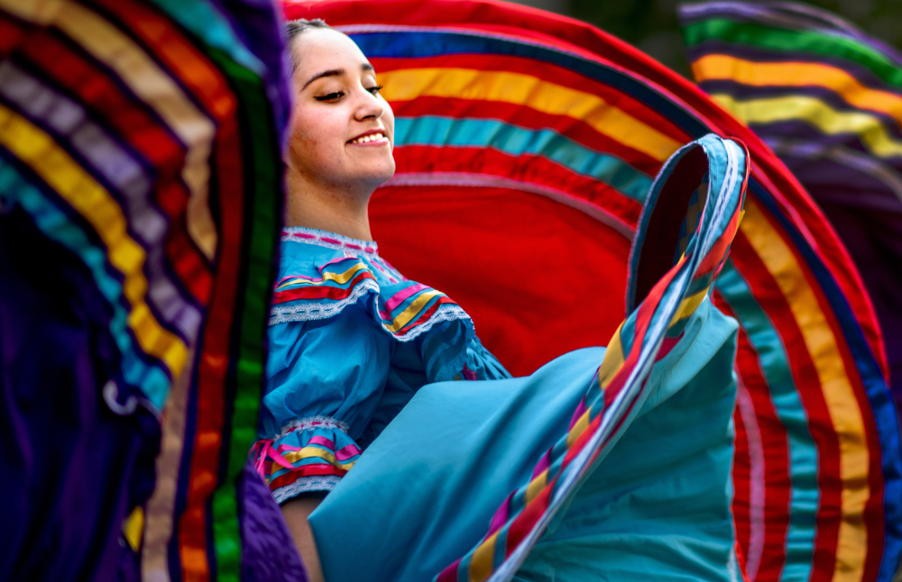 woman in colorful, cultural Hispanic dress dancing and swinging skirts