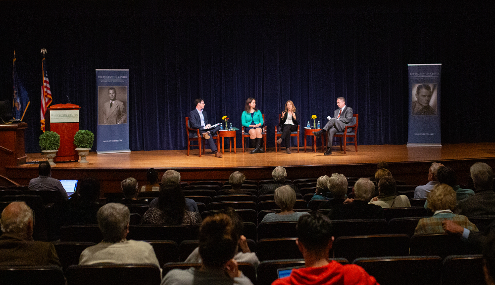 four people seated on stage, two Hauenstein Center for Presidential Studies vertical banners on stage left and right