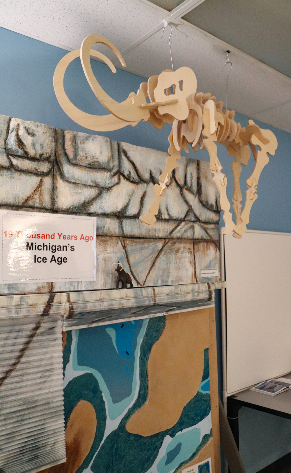 wooden cutout of prehistoric mammal hanging from ceiling