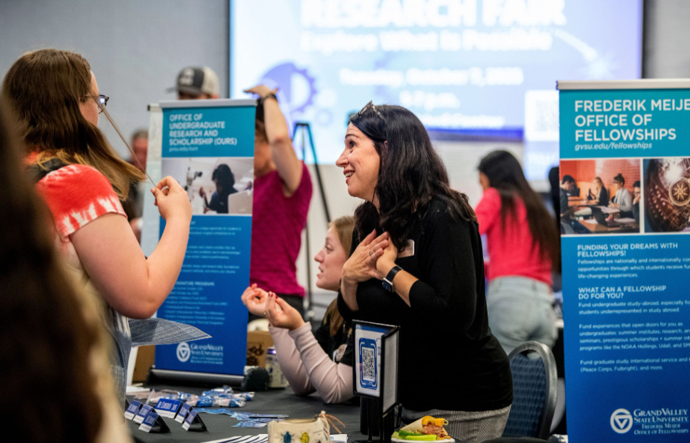 Susan Mendoza, in center, with hands over heart chatting with someone at the undergraduate research fair