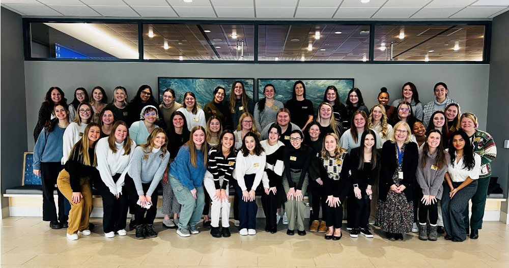 large group of people posing for a photo in a hallway