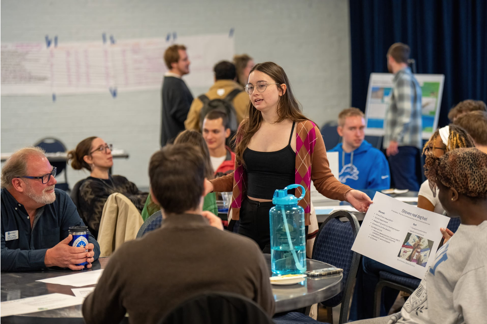 Alison Armstrong shows research on a paper to a table of people seated