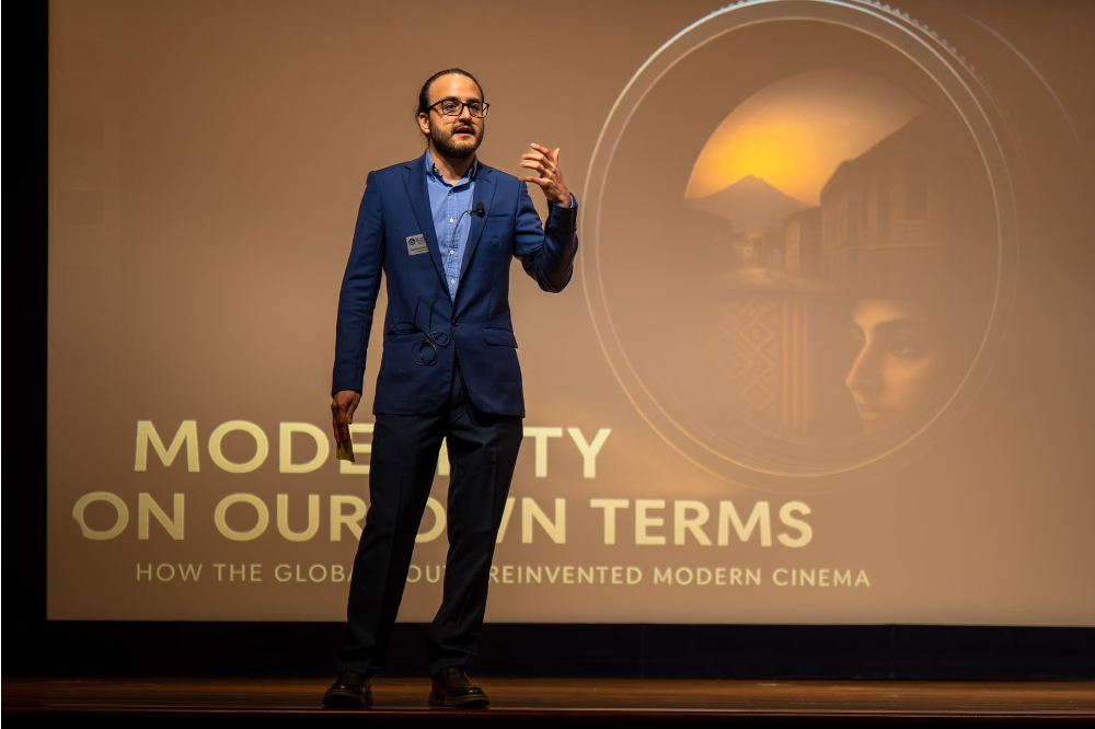 Navid Darvishzadeh stands on stage in front of a screen that reads Modernity On Our Own Terms