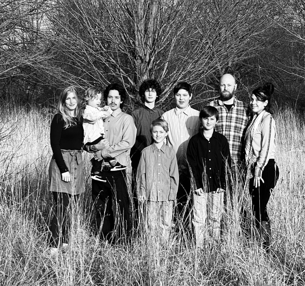 family photo of nine people in front of tree, in black and white