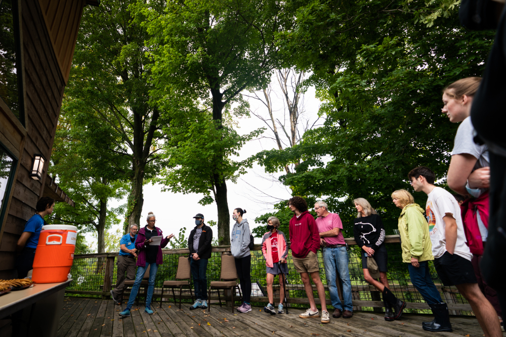 group of people standing in semi-circle outside in Grand Ravines Park with forest of trees behind them
