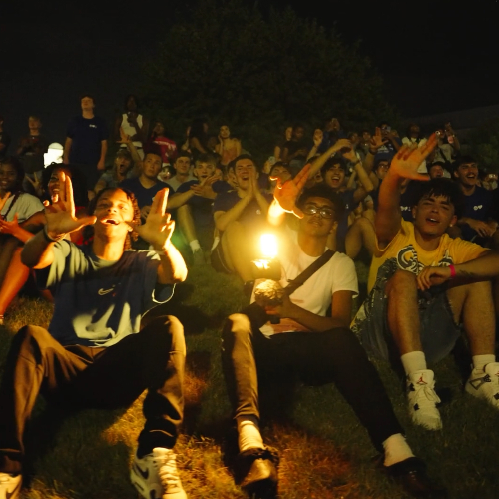 students seated on ground during fireworks show