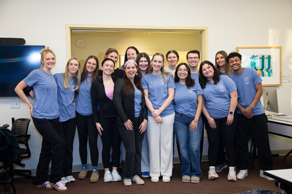 group of students in two rows, many in light blue t-shirts
