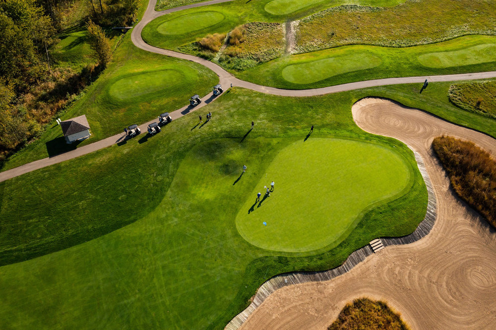 drone photo of the Meadows Golf Club, a green and cart path shown with several carts