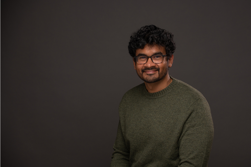 Sanjivan Manoharan in olive sweater and glasses