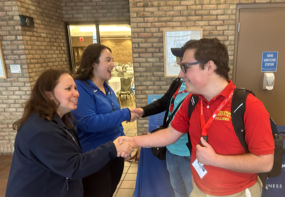two pairs of students shaking hands