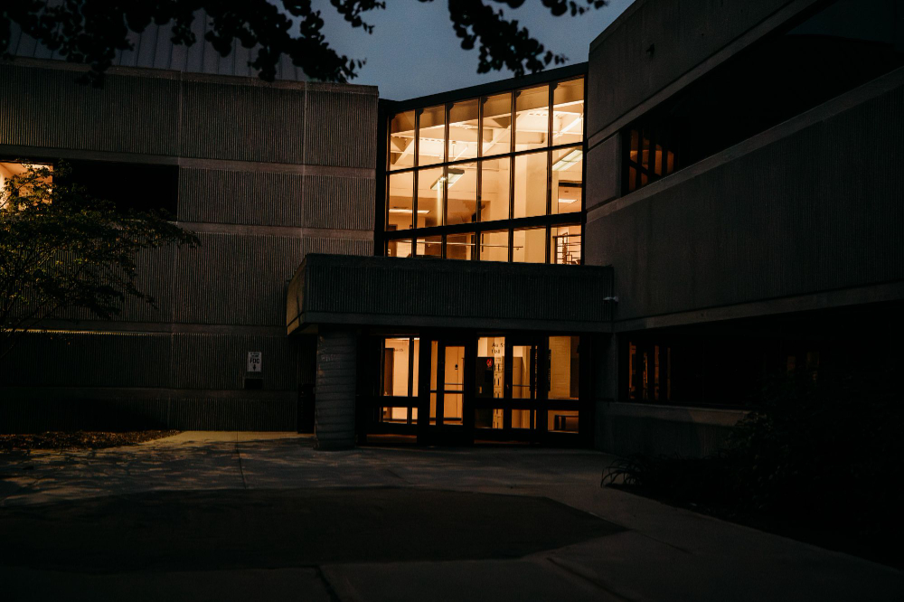 campus building at night with only light from entry way lit