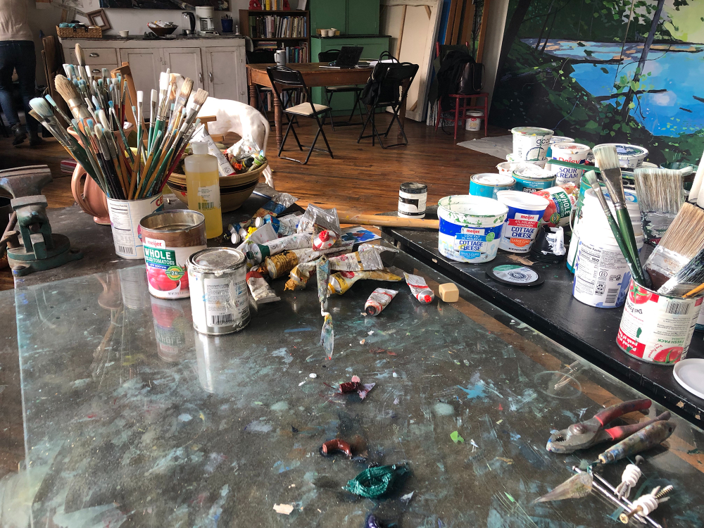 paint brushes, containers of paint, some paint on palatte
