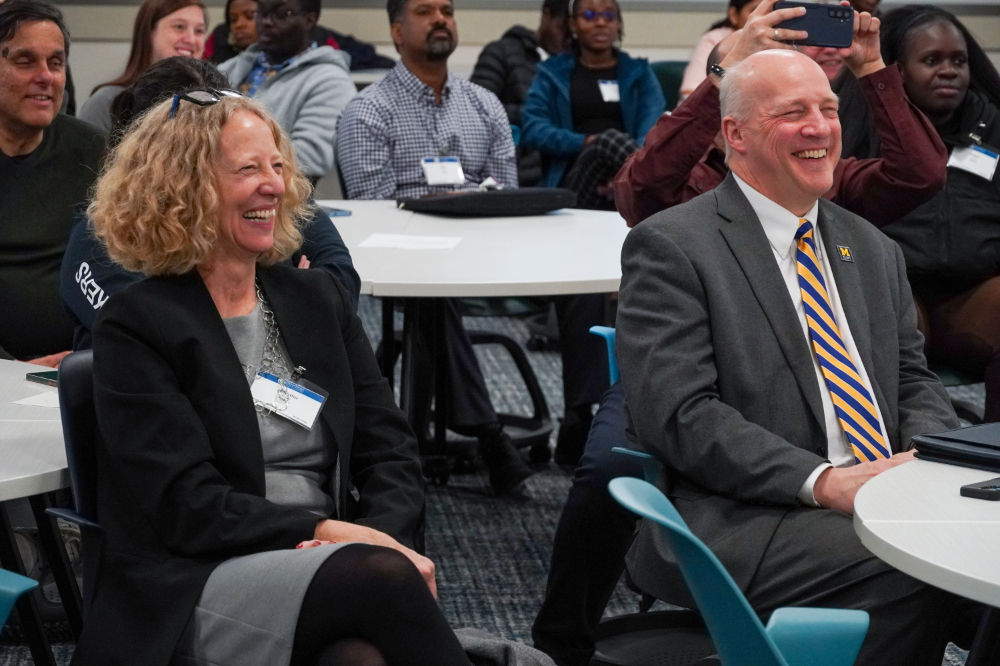 two people seated laughing, others in background