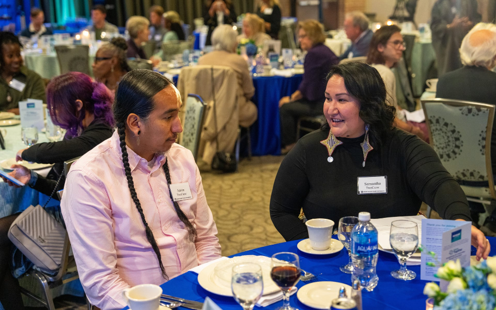 two people seated at round table, chatting