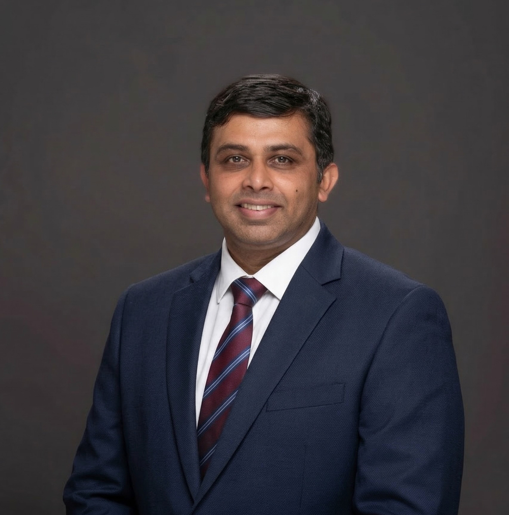 Imran Mazid in blue jacket and white shirt, striped tie