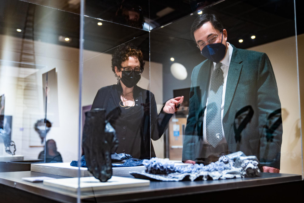 two people look at a display case at an art exhibition