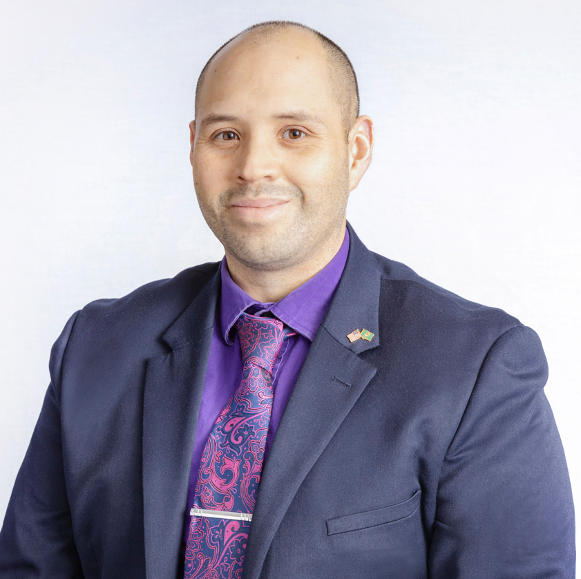 Julian Ramirez-Torres portrait, he is wearing a dark suit coat and purple shirt and tie