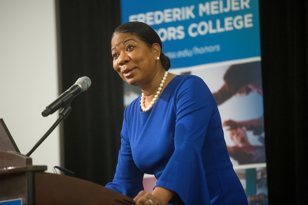 Dara Richardson-Heron at podium addressing audience in front of a vertical banner for the Frederik Meijer Honors College