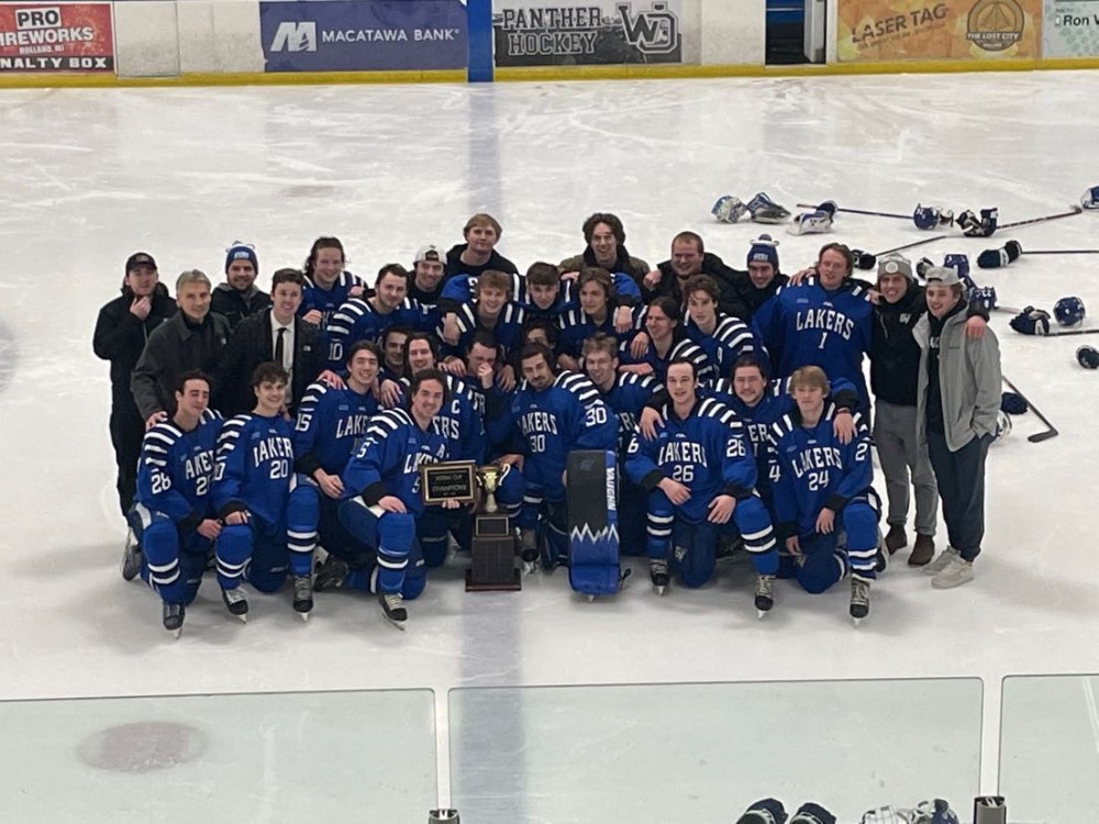 hockey players, coaches and staff members pose for a photo with a trophy on the ice at a hockey rink