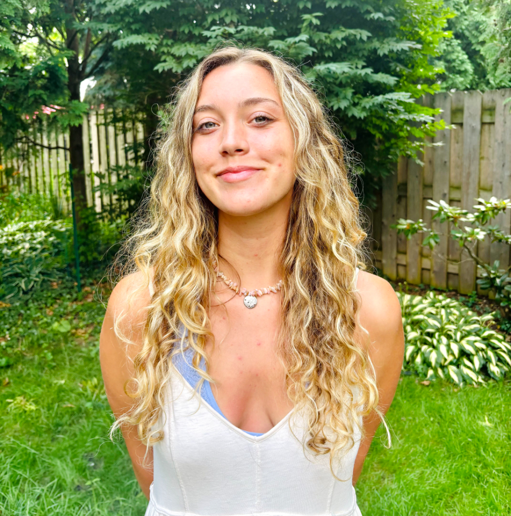 Jacqueline Listman outside in backyard with white tank top on