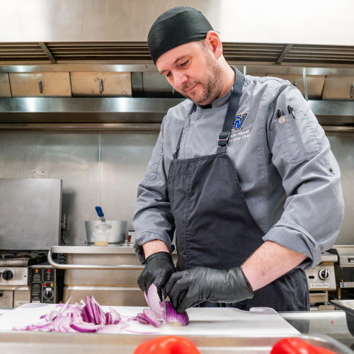 chef chopping onions in commercial kitchen
