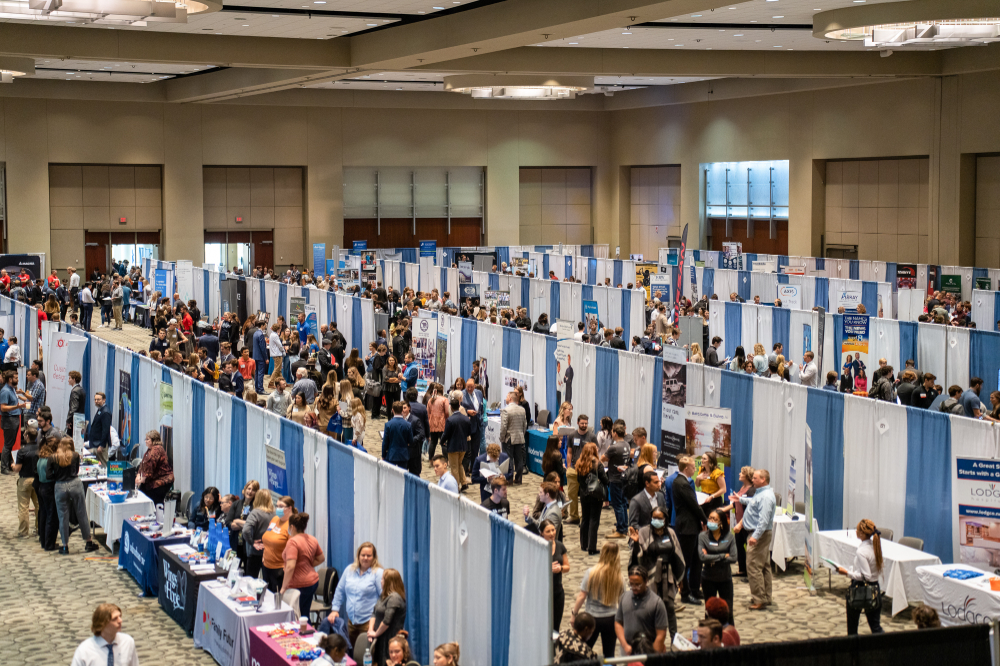 people walk among rows of booths at the career fair, held at the DeVos Place Convention Center