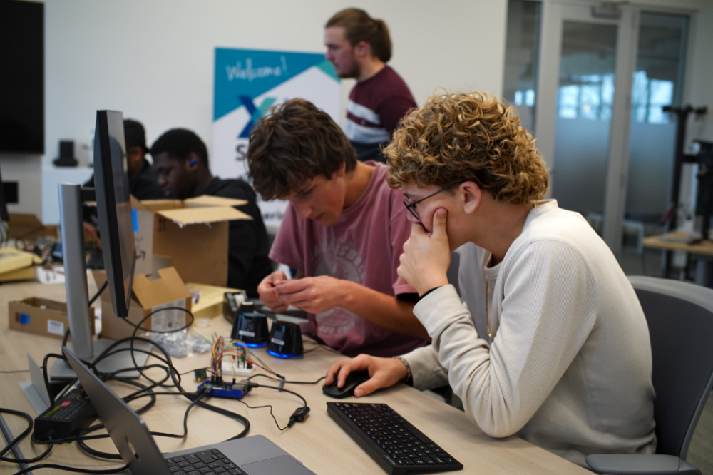 students at computer table with parts out in front of them to tinker with