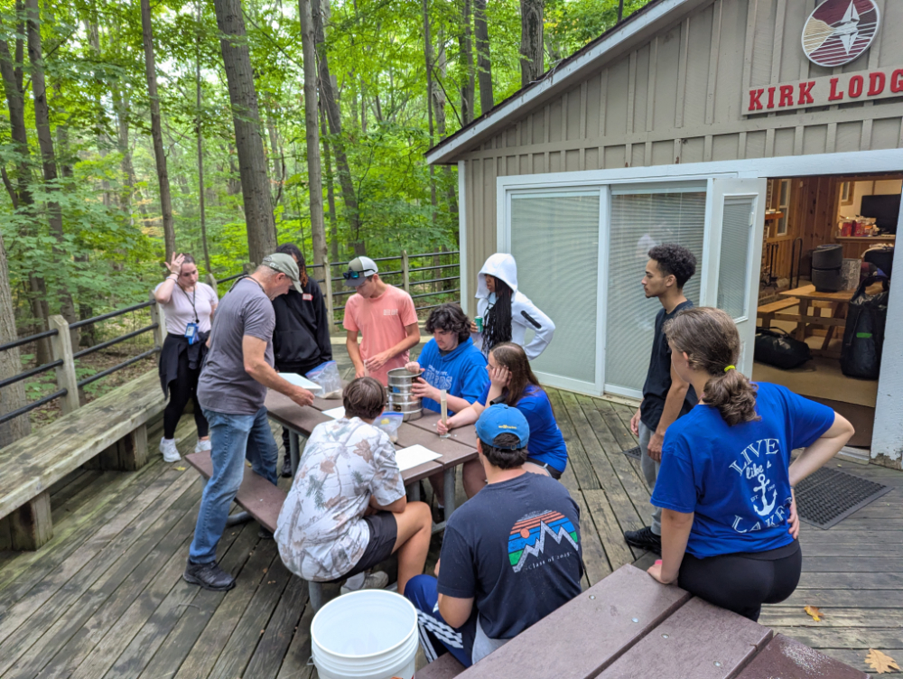 group sitting or standing near picnic table at Kirk Lodge