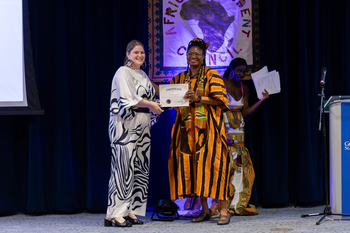 two people each holding a certificate and dressed in traditional African outfits
