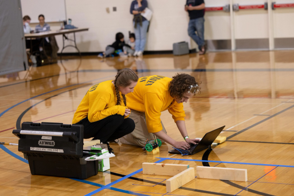 two young students on the floor of the Fieldhouse during a Science Olympiad event
