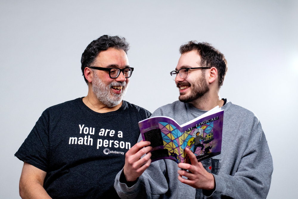 John, left, and Xavier Golden look at each other while Xavier holds a book they completed together. John's shirt: you are a math person