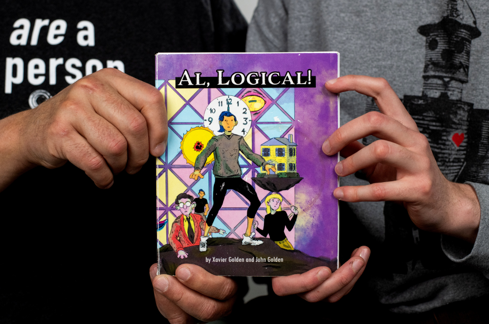 two sets of hands holding a book, AL Logical. The cover is mostly purple