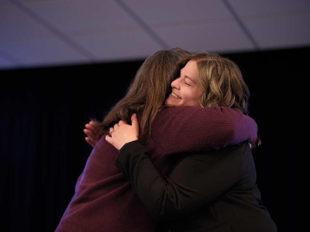two women hugging on stage