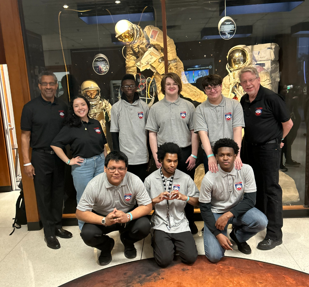 two rows of people, front group kneeling, in front of an astronaut in Houston at the Johnson Space Center