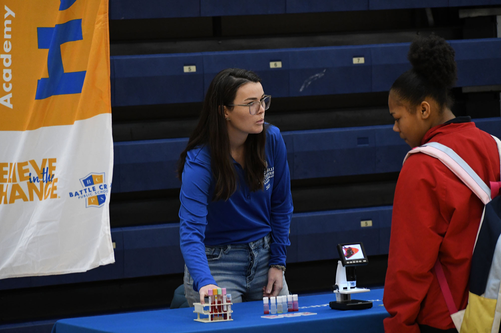 Mattie Brechbiel, affiliate faculty and clinical laboratory coordinator for Medical Laboratory Sciences, talks with a student at the career fair. Small vials are on the table.