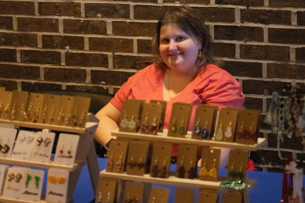 Arianna Kraljic sits behind a display of earrings and other jewerly