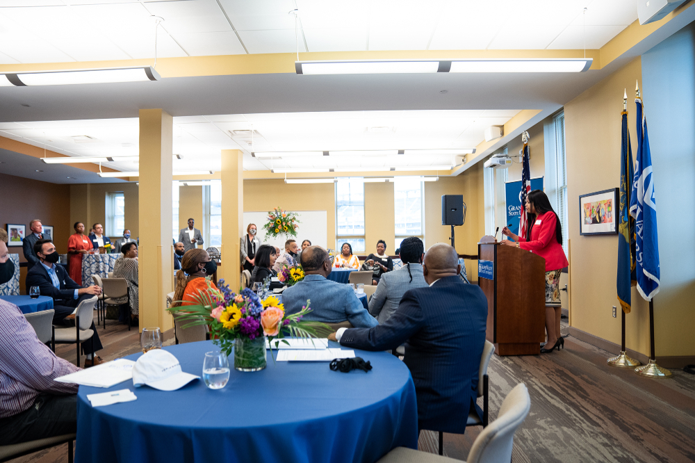 Mikyia Aaron talks to the audience from a podium at the Detroit Center