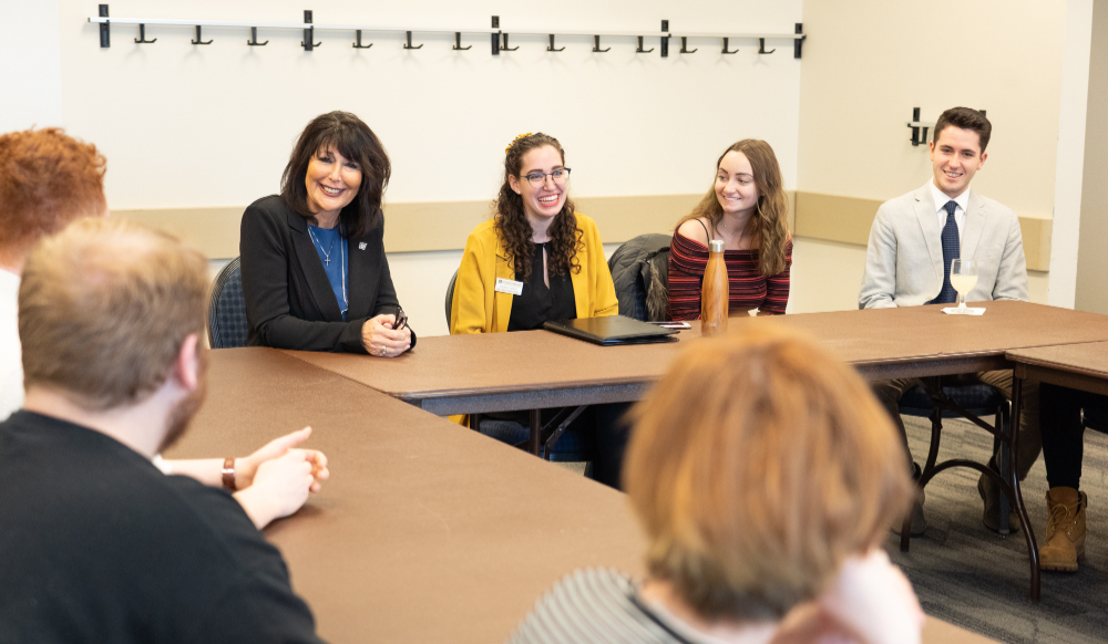 President Mantella meets with students, all seated around conference tables