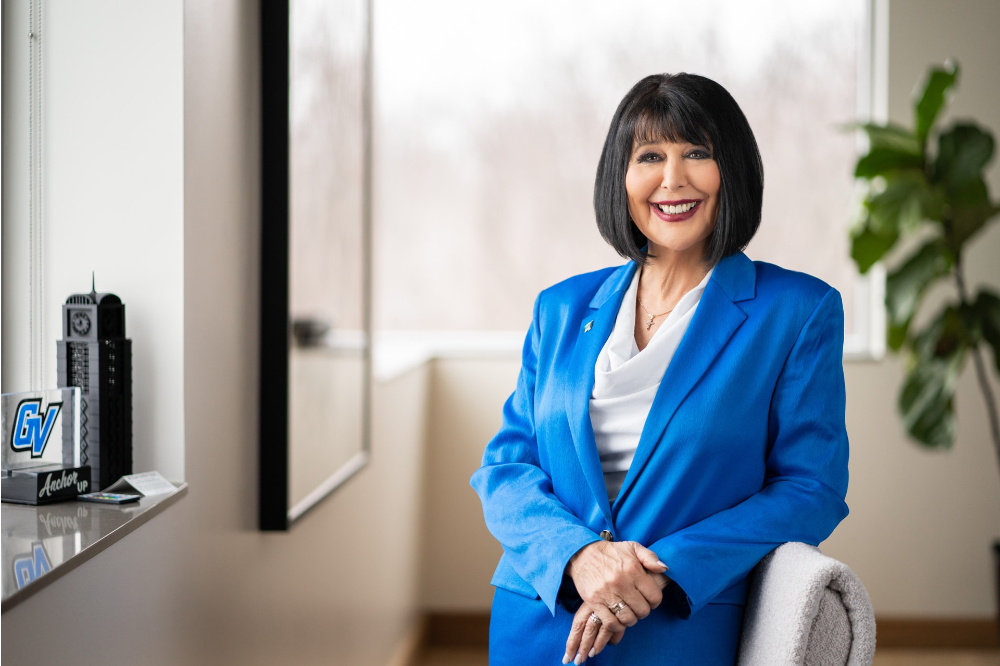 President Mantella in blue jacket and skirt leaning on a chair in her office