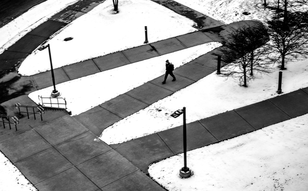 person on sidewalks, black and white photo, snow on ground