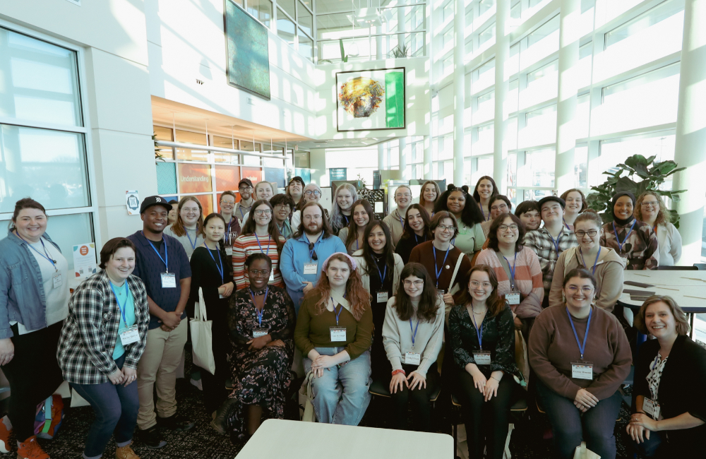 large group of students standing and seated for group photo in atrium of DCIH
