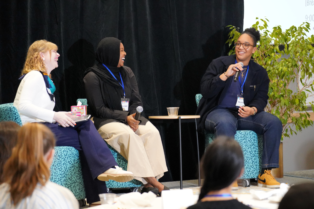 three people in chairs at front of room leading a discussion
