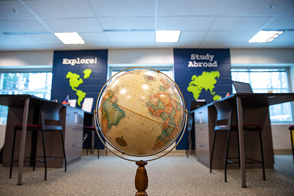 a globe placed on the floor, in the background are two vertical banners, Explore! and Study Abroad