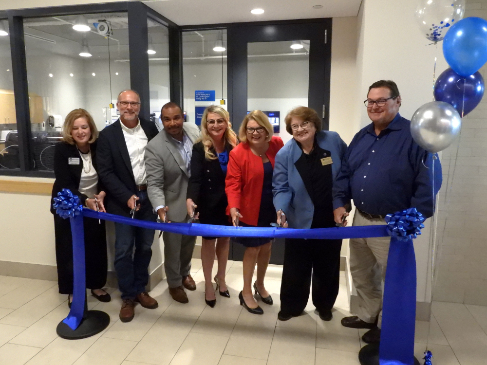 seven people behind a ribbon, ready to cut it