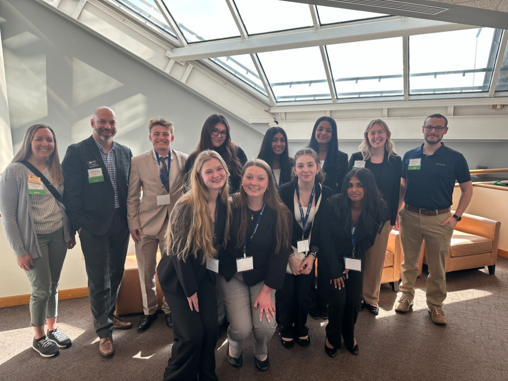 two rows of people standing in hallway under skylights, four people in front crouching down slightly