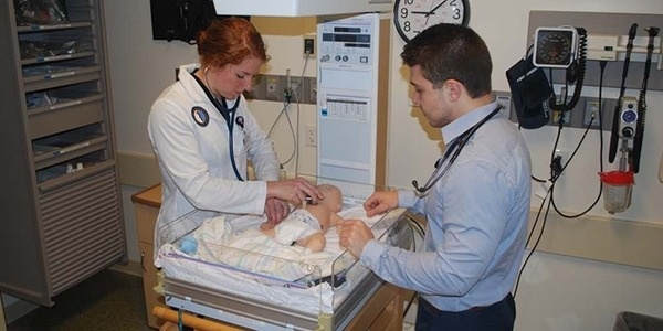 Two students practicing on a simulation infant mannequin.