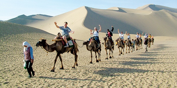 Students on a study abroad trip riding on camels.
