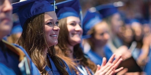 Students sitting in their cap and gown at commencement