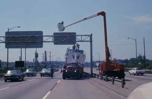 An old photo of the angus boat being transported by truck along a highway